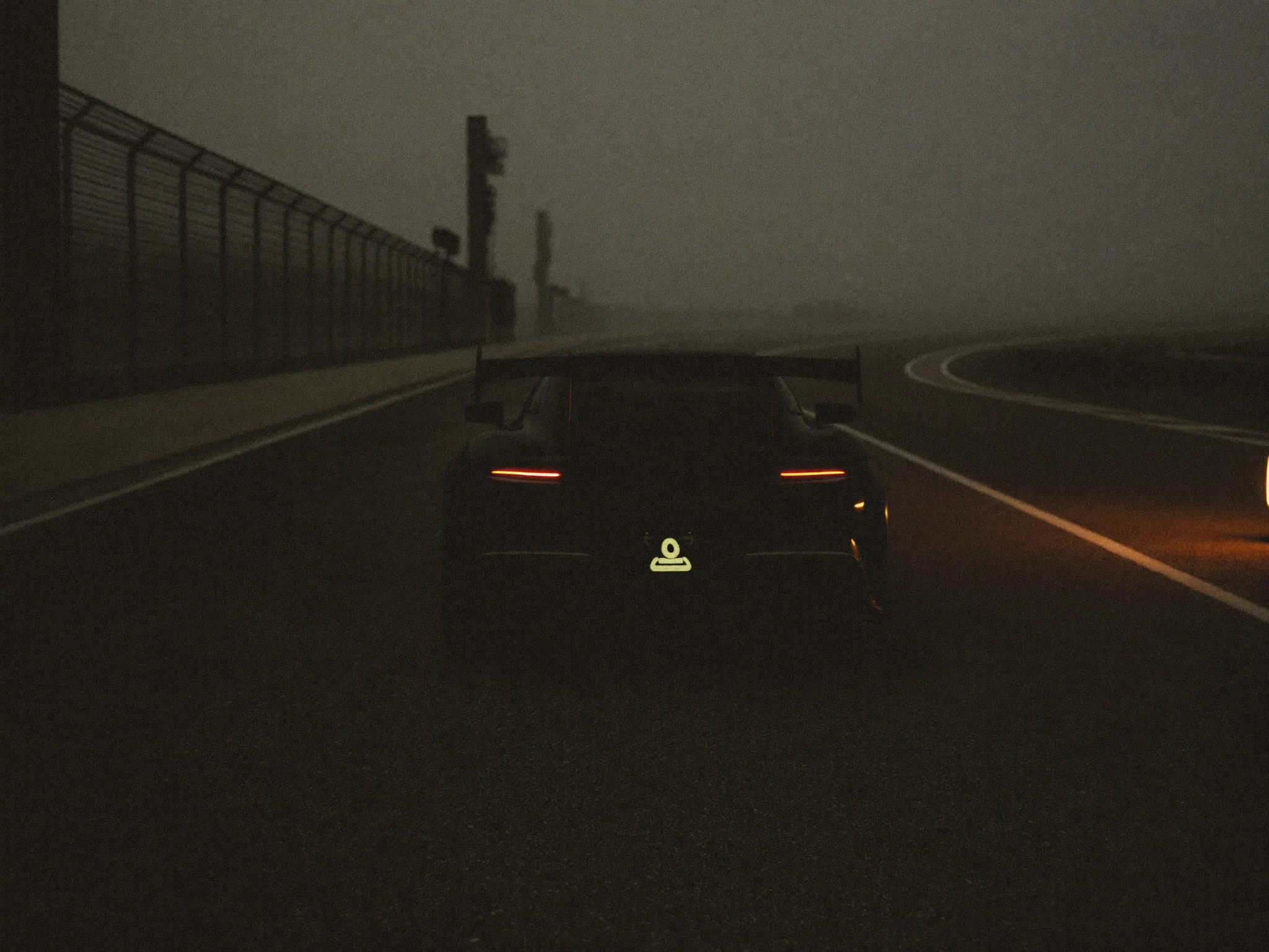 Lone sports car in dawn fog on an empty pit straight