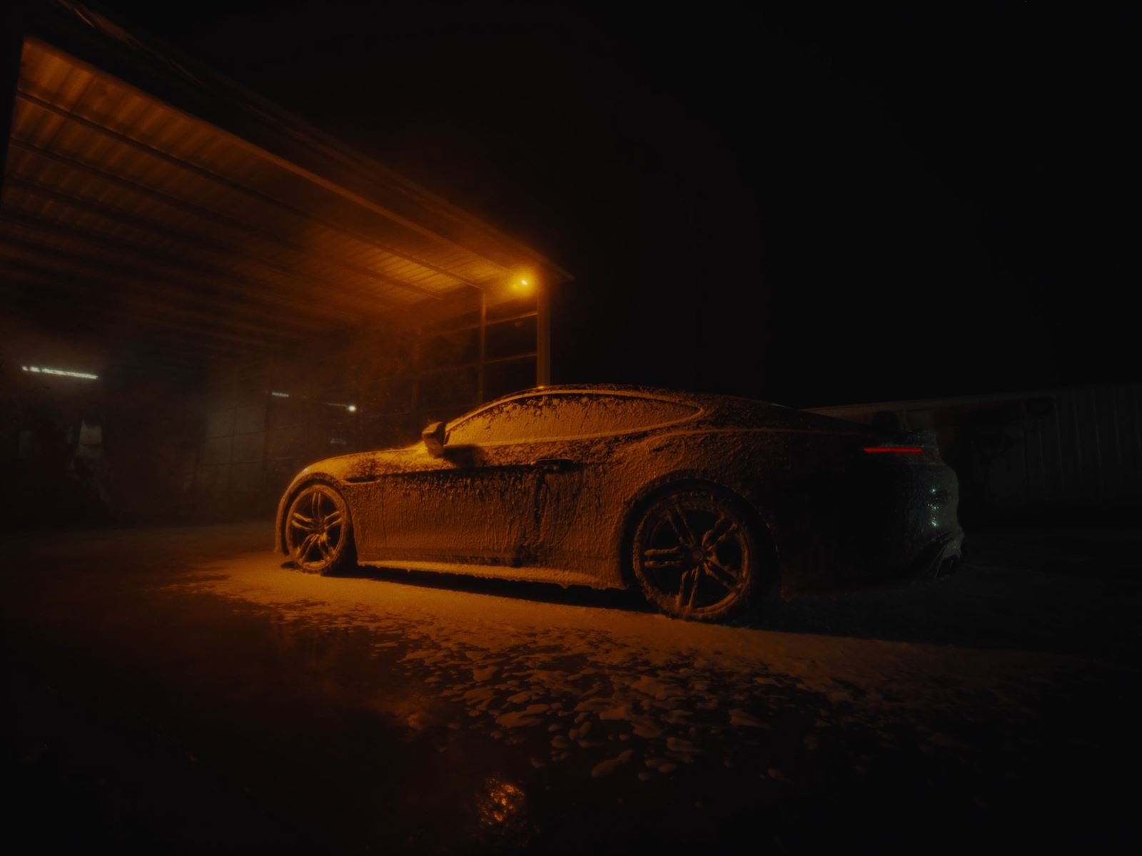 Foam-covered car in a self-service wash bay at night