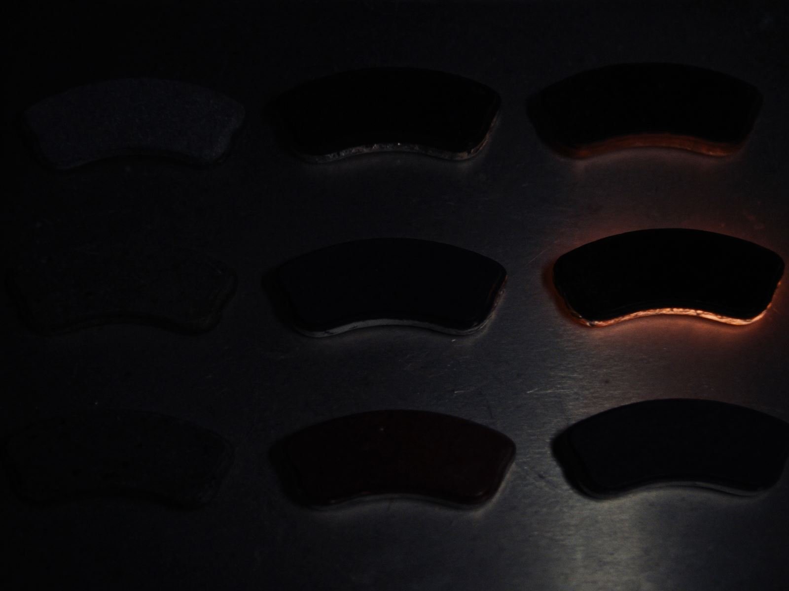Different brake pads arranged on a dark workbench