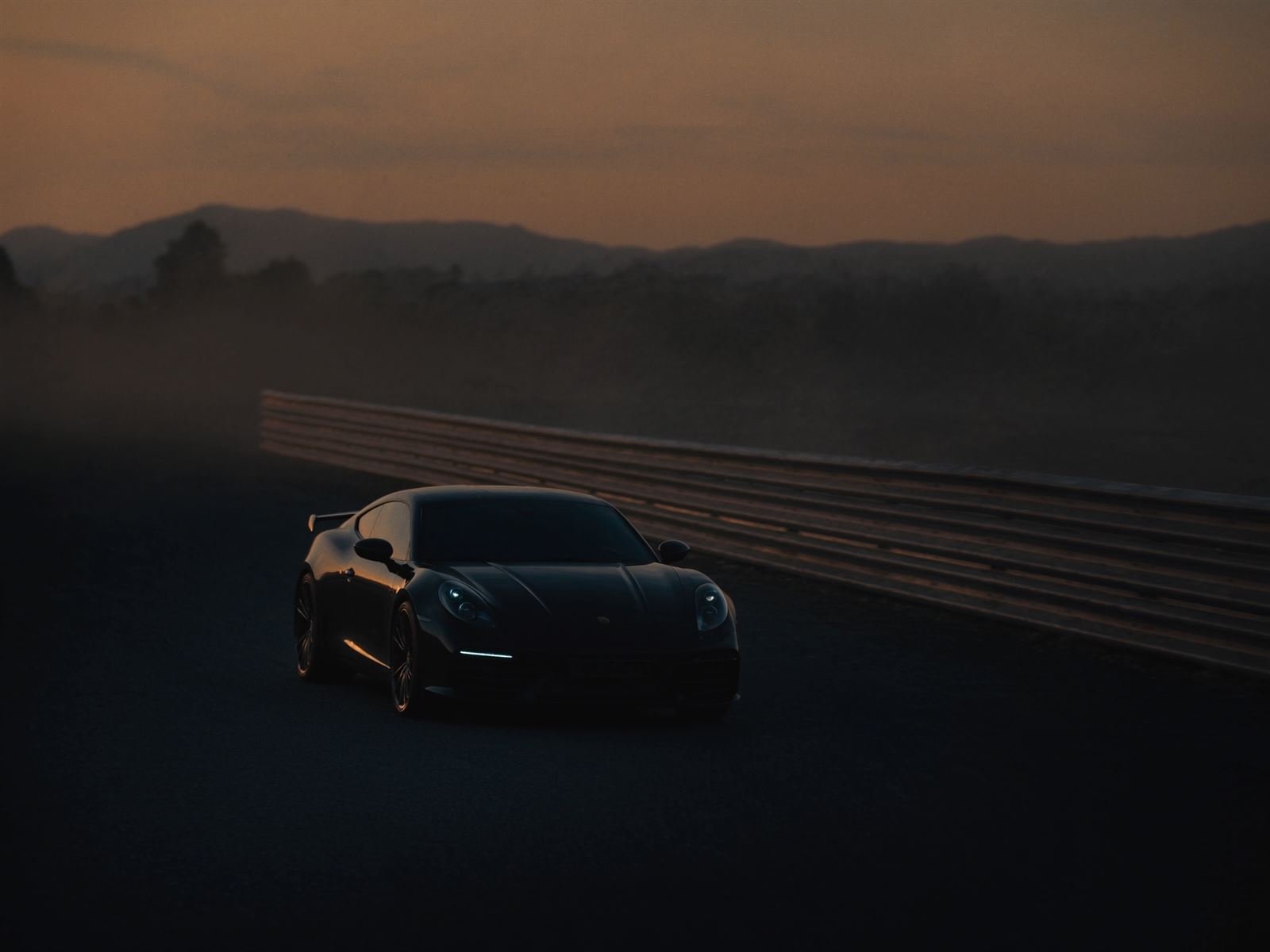 Sports car beside an armco barrier on a misty circuit at dawn